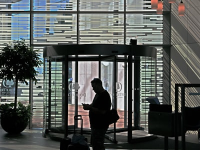 a man standing in front of a tall glass building